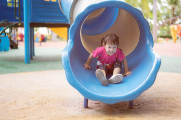 Asian baby girl playing slider at playground in the park.