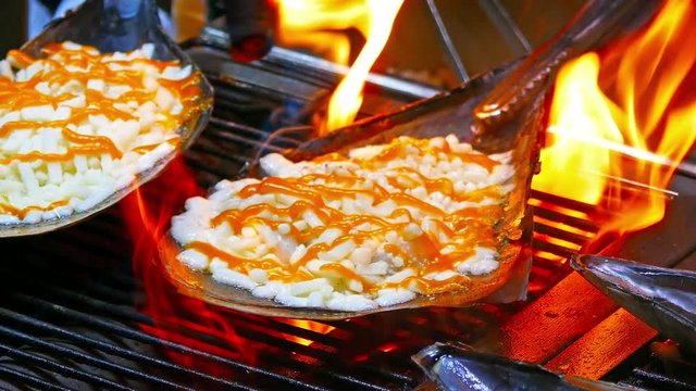 Cheese flame grilled in an oyster half shell on barbecue outdoor setup in Myeongdong Market. - Close up