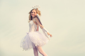 Fototapeta na wymiar Charming curly little girl in white dress and wings - angel cupid girl. Enjoying magic moment. Angel child girl with curly blonde hair - Innocent girl concept.