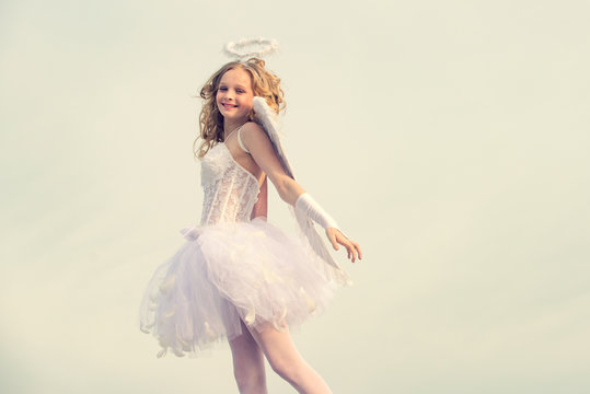Charming curly little girl in white dress and wings - angel cupid girl. Enjoying magic moment. Angel child girl with curly blonde hair - Innocent girl concept.