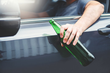Drunk man driving a car on the road holding bottle beer Dangerous drunk driving concept