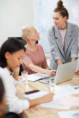 Portrait of two contemporary businesswomen using laptop while discussing project development in...
