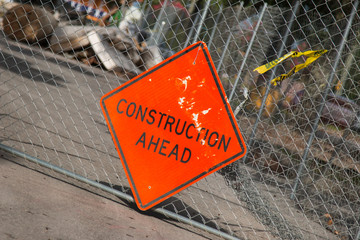 Construction Ahead sign on a chain link fence work site. - 274804499