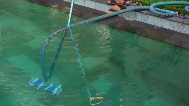 Young man professional swimming pool cleaner does pool cleaning service