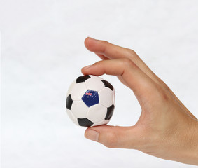 Fototapeta premium Mini ball of football in hand and one black point of football is Australia flag, hold it with two finger on white background.