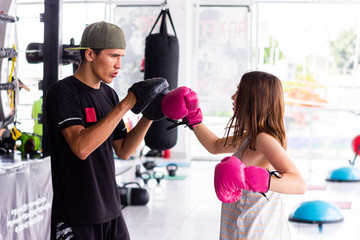 chica entrenando con guantes sacos de entrenamiento en gimnasio entrenador rosa