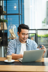 Making online bank transfer, man holds a credit card while entering data in laptop for shopping concept.