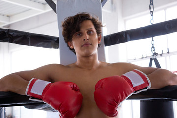 Hombre en ring de box entrenando con guantes sacos de entrenamiento en gimnasio entrenador
