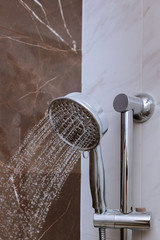 Naklejka na ściany i meble Fresh shower with water drops splashing. Water running from shower head and faucet in modern bathroom.