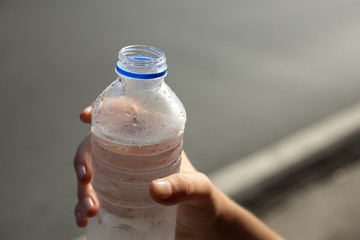 A hand holding a plastic bottle of cold water closeup