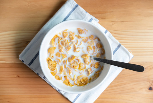 Healthy breakfast with corn flakes and milk on wooden table, Top view