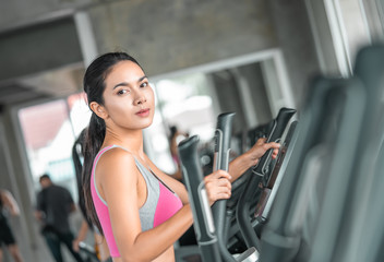 Female in pink sport wear is working out on Step climber machine in fitness gym for healthy...