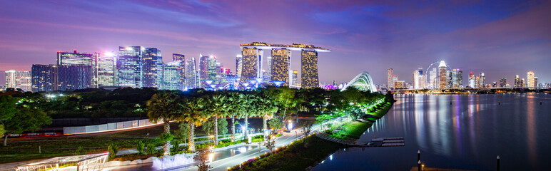 Fototapeta premium SINGAPORE, SINGAPORE - MARCH 2019: Vibrant Singapore skyline with Marina Bay Sands, Gardens by the bay with cloud forest, flower dome and supertrees at sunset. Top view from marina barrage