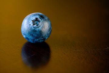 One fresh ripe blueberry isolated with copyspace on an old wooden table background