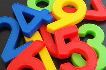 Fototapeta premium Colorful plastic numbers on dark table 