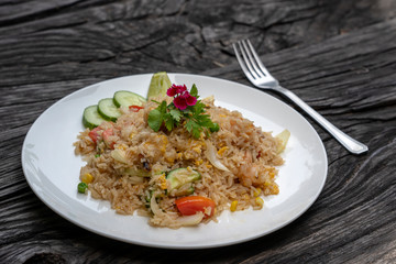 Fried rice with shrimps and vegetables in a white dish on an old wooden table, close up . Thai food...