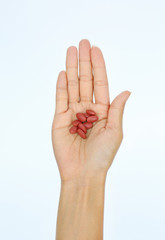 Close-up hand of a woman with some pills on white background