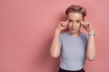 Pink-haired young woman wipes fake tears, pink background