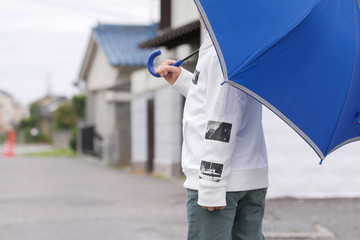 登下校中に雨の日に傘を持った少年 