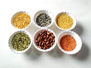 Uncooked pulses,grains and seeds in White bowls over white background. selective focus