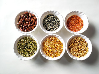 Uncooked pulses,grains and seeds in White bowls over white background. selective focus