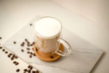 Ice coffee in the glass topped whipping cream with coffee beans. Cold summer drink on wooden background and copy space. Advertising for caramel mocha and chocolate beverage for the cafe.