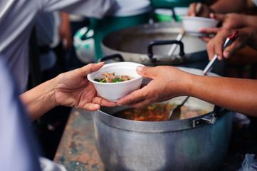 volunteers giving food to poor people in desperate need : The concept of food sharing Help solve Hunger for the homeless