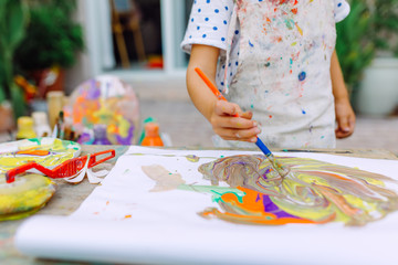 Little cute girl painting in the garden and mixing different colors