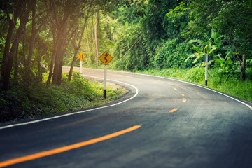 Obraz premium The curved road in the forest with traffic sign. Concept road to success