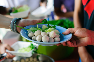 Poor people receiving food from donations : Homeless people are helped with food relief, famine relief : volunteers giving food to poor people in desperate need