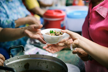 The concept of social sharing : Poor people receiving food from donations : Homeless people are helped with food relief, famine relief : volunteers giving food to poor people in desperate need