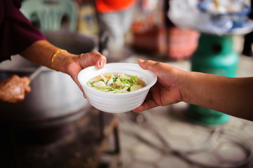 Feeding Concepts : Hand offered to donate food from a rich man Share : The concept of social sharing : Poor people receiving food from donations
