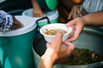 Feeding Concepts : Hand offered to donate food from a rich man Share : The concept of social sharing : Poor people receiving food from donations