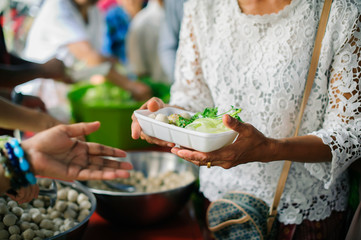 The concept of humanitarianism : The hands of refugees have been aided by charity food to alleviate hunger : Feeding Concepts : Hand offered to donate food from a rich man Share