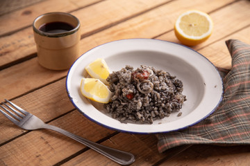 Plate of black rice with squid and prawns or Valencian black paella