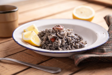 Plate of black rice with squid and prawns or Valencian black paella