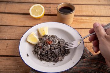 Plate of black rice with squid and prawns or Valencian black paella