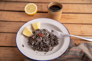 Plate of black rice with squid and prawns or Valencian black paella