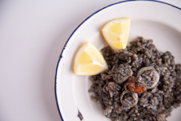 Plate of black rice with squid and prawns or Valencian black paella