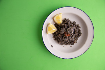 Plate of black rice with squid and prawns or Valencian black paella
