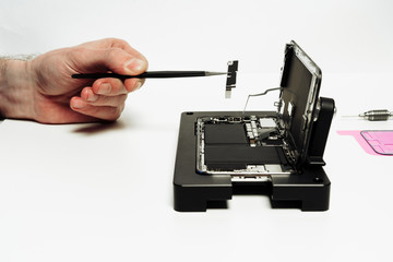 Repairman Assemble Disassembled Open Smartphone. Engineer Hand with Forceps Holding Detail Motherboard Chip Isolated on White Background. Technician Service Center for Fixing Damaged Mobile Phone
