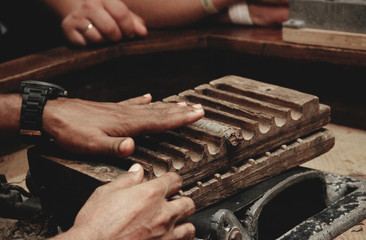 Traditional cigar production. Hands close-up twist cigars from tobacco leaves