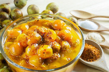 Ceylon oak in glass bowl peel reveal appetizing orange fruit on wood table. thai fruit. Schleichera oleosa (Lour.) Oken. Nephelium hypoleucum. Sapindaceae. Livistona speciosa.