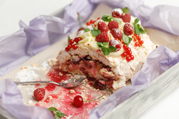 Small spoon and delicious meringue cake with ripe fruit are on a tray
