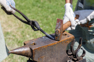 Blacksmith hammering on a metal billet lying on the anvil