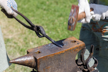 Blacksmith rhythmically hammering on a metal billet lying on the anvil