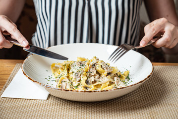 woman eating Spaghetti Carbonara with chicken and cheese.