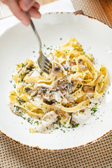 woman eating Spaghetti Carbonara with chicken and cheese.