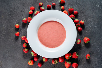 Obraz na płótnie Canvas Strawberry Gazpacho Delicious Sweet Dish Top View. Tasty Cold Soup Made of Blended Natural Red Ripe Berries in White Plate Isolated on Black Background. Refreshing and Cool Classic Spanish Cuisine