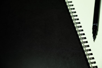 blank page notebook and pen against dark background